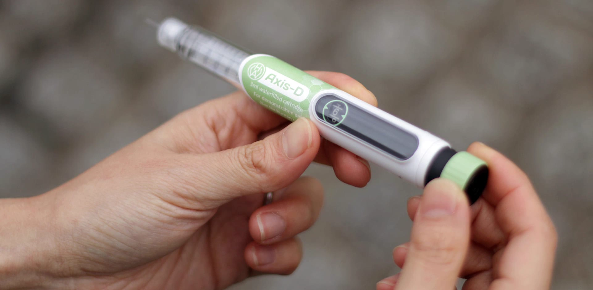 Hands holding the Axis-D injection pen